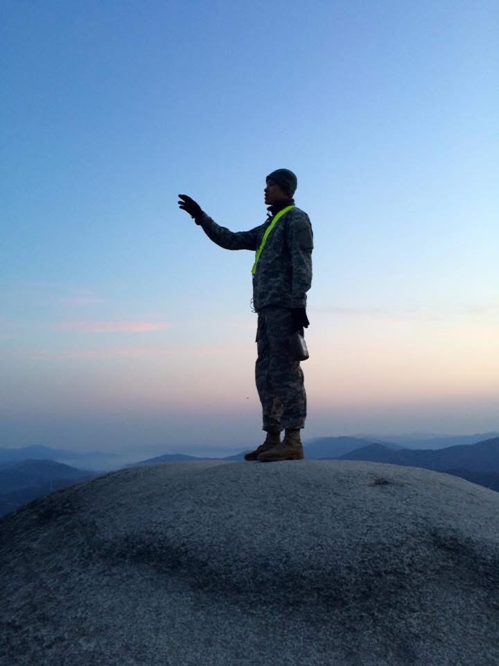 Veteran on a rocky summit at dawn, looking toward the horizon